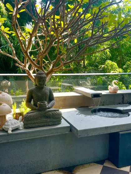 A close-up of the Buddha statue and the custom-designed water feature, showing the details of the stone and the gentle flow of water.