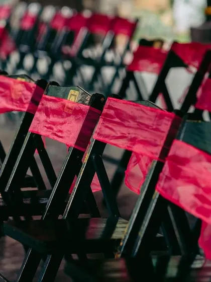Black chairs are given a pop of color with bright pink sashes, adding a festive touch to the guest seating area.