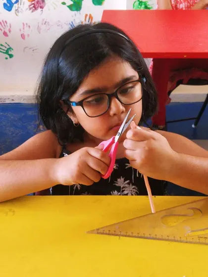 Using a ruler and scissors, this student measures and cuts her materials precisely for the straw construction project.