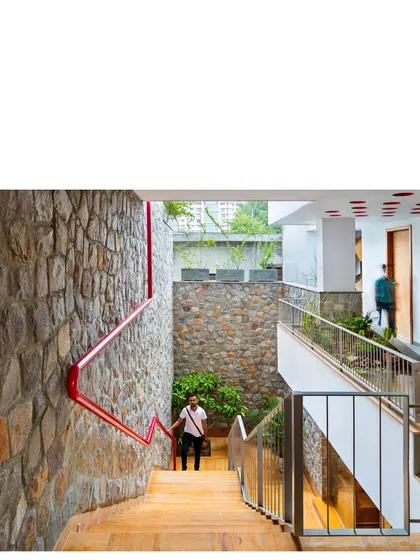 The red handrail is a functional sculpture, guiding movement through the space while channeling overflow water from the upper levels to an underground storage tank.