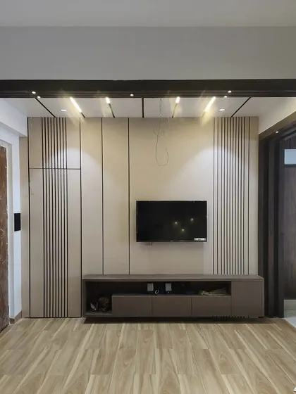 This living room TV unit is still under construction but shows the combination of fluted panels and smooth laminates. The design includes integrated lighting within the ceiling beam.