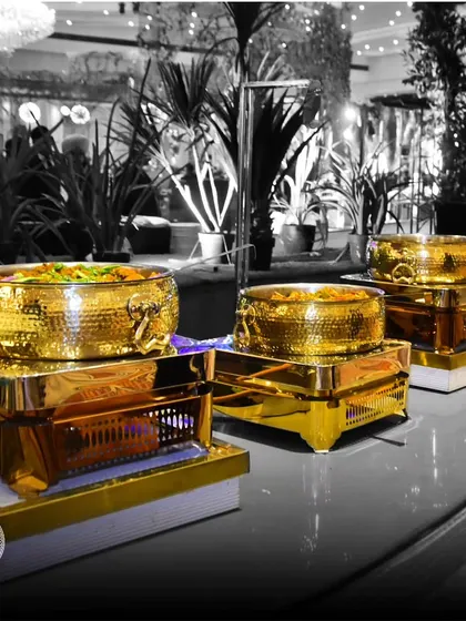 A black and white shot with a pop of color, highlighting our gleaming gold-tone chafing dishes. This artistic photo emphasizes the luxury and design of our buffet presentation.