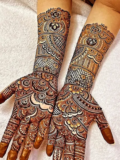A modern take on bridal mehendi, this design uses bold checkerboard patterns (jaali) and negative space to make the floral and paisley elements pop. It's a statement look that is both traditional and contemporary.