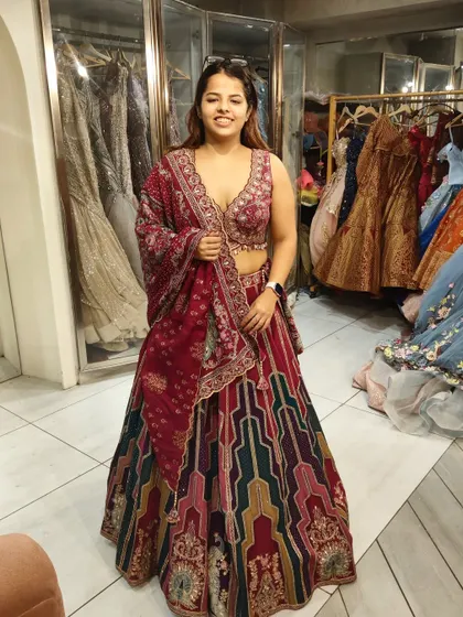 A happy client trying on a vibrant multi-color lehenga. The mix of patterns and colors makes it a perfect choice for a lively Mehendi or Sangeet event.