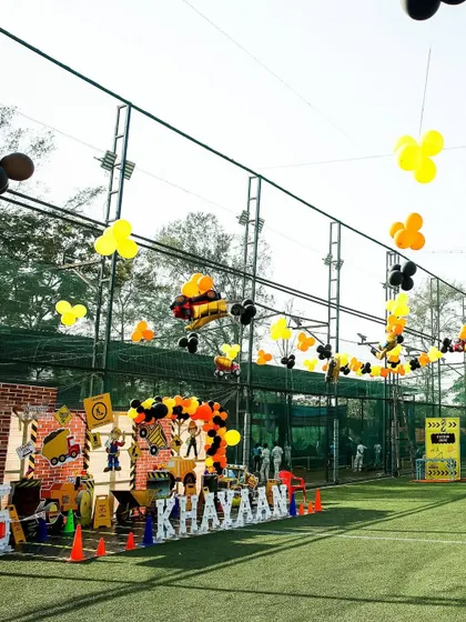 A wide view of the outdoor construction party, showing the main stage, activity zones, and balloons floating above the play area.