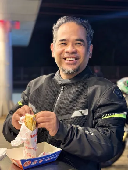A fat and juicy smile, at your service. A candid shot of me enjoying a meal, probably after a long motorcycle ride, which is my therapy.