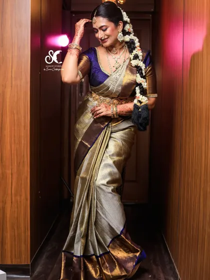 This full-length shot showcases the art of saree draping. The pleats are neat and the pallu falls perfectly, creating a graceful silhouette that enhances the bride's entire look.