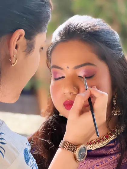 A behind-the-scenes shot of me creating a vibrant look with pink eyeshadow and a red lip for a wedding guest.