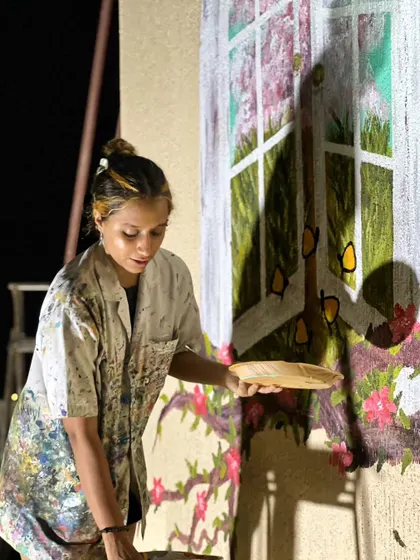 Me painting the whimsical window mural on the terrace, adding details to the flowers and branches.