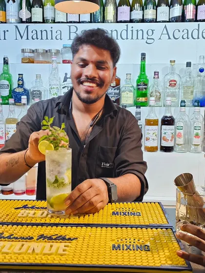A bartender from our Goa branch with a classic Mojito, expertly muddled and garnished.