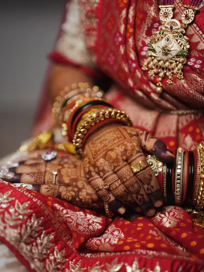 Another angle of the stunning bridal mehendi, focusing on the rich detail of the henna against the bride's traditional red and white lehenga.
