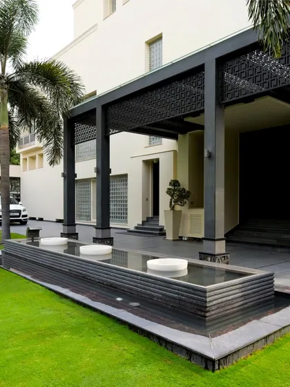 A minimalist water feature runs alongside the home's entrance, reflecting the clean lines of the architecture. This design uses water to create a sense of tranquility and separation between the driveway and the main living areas.