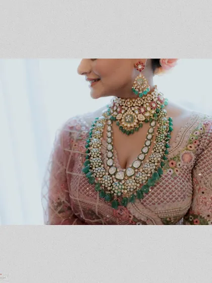 A close-up on the bride's stunning multi-layered necklace and her gentle smile.