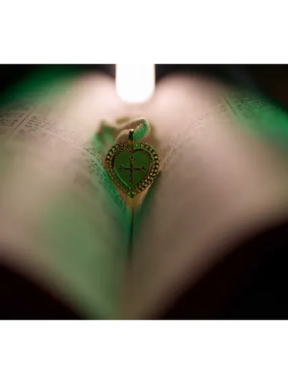 A symbolic image of a heart pendant placed within the pages of a book, signifying the beginning of a new chapter together.