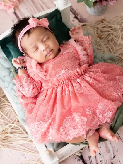 An overhead view of the baby girl in the pink lace dress, showing her peaceful expression as she sleeps.