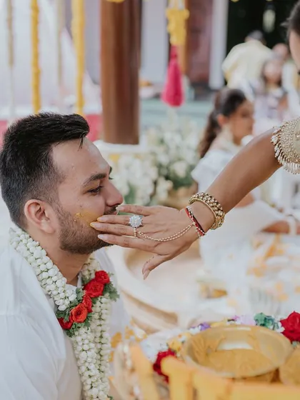 A tender moment during the Haldi ceremony where a family member applies turmeric paste to the groom.