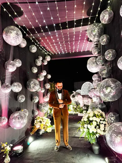Sangeet is magic. Posing in a stunning disco ball-themed entrance tunnel, ready to host a night of glamour and entertainment.