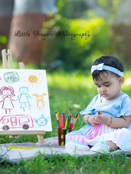 This little angel is contemplating her next color choice for her family drawing. The 'Little Artist' theme is a beautiful way to capture their budding creativity.