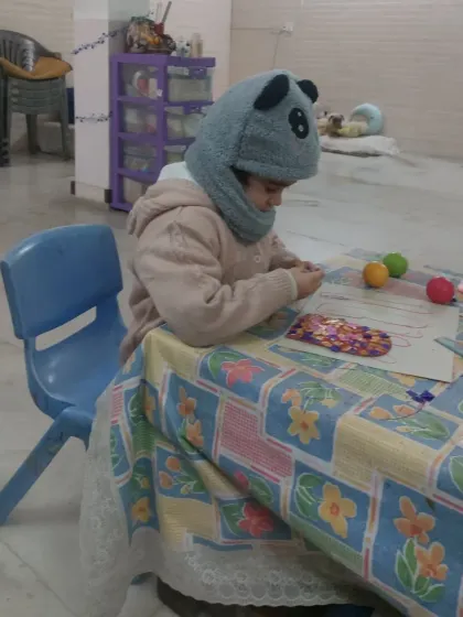 A preschooler deeply focused on her craft project. Our sessions are designed to hold the attention of even the youngest learners through engaging and age-appropriate activities.