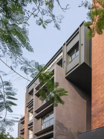 Close-up details of the ARCUS facade, highlighting the texture of the brickwork, the depth of the balconies, and how the structure was designed to accommodate existing trees.