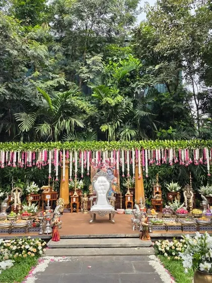 An outdoor puberty ceremony setup that blends with the natural garden surroundings. I created a floral canopy with hanging jasmine and rose garlands, a central white throne, and a beautiful arrangement of sacred props and offerings on a raised platform.