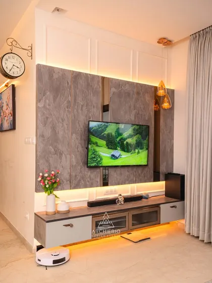 A modern TV unit with a grey stone-finish back panel and integrated ambient lighting. The design is sleek and minimalist, with a hanging clock adding a touch of vintage charm.