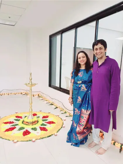 Santoshi and Srideep standing by a beautiful rangoli. This image captures their shared joy in celebrating festivals and traditions together as a couple.