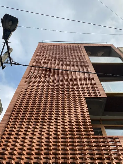 An upward view of the 'Brick Weave House' facade during construction.