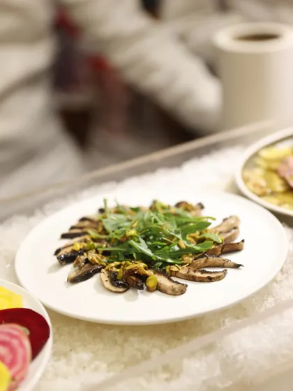 A platter of grilled mushroom salad with arugula, served on a bed of ice to keep it fresh. Our cold buffet selections are crafted with the same care and attention to detail as our hot dishes.