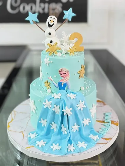 A magical two-tiered cake inspired by Disney's Frozen. This design features Queen Elsa, a flowing fondant dress, and delicate snowflake details, making it a dream come true for any young fan.