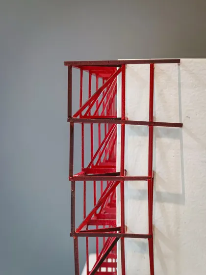 A detailed view of the red conceptual model, highlighting the diagonal bracing of the proposed metal lattice structure.