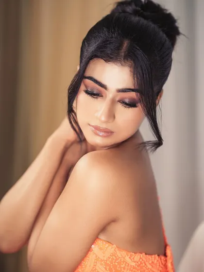 This image captures a soft, glamorous makeup look that perfectly complements the vibrant tone of the orange dress.