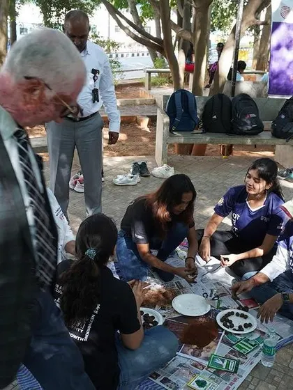 An official observing the students during the seed ball making workshop at Ramaiah University. These events often attract positive attention for their community impact.