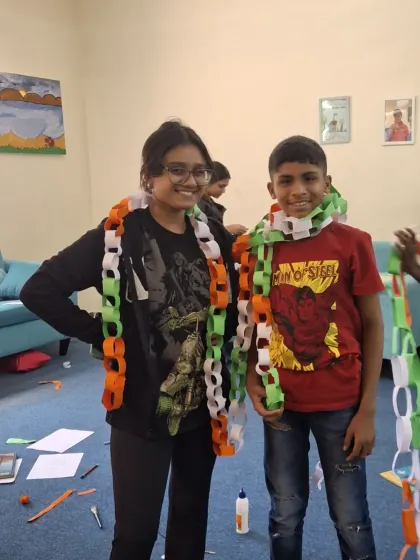 A volunteer and a child playfully wear the tri-color paper chains they made. These moments of shared fun and laughter are what make our celebrations so special.