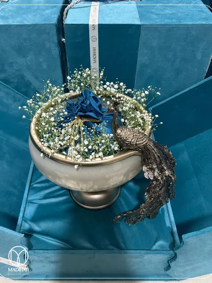 An overhead view of the Peacock Bowl in its blue velvet box. The bed of baby's breath adds a soft, delicate touch, making the gift feel even more special.