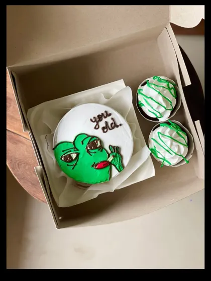 A funny birthday combo featuring the "You old" meme on a bento cake, accompanied by two cupcakes with matching green frosting. It's sure to get a laugh.