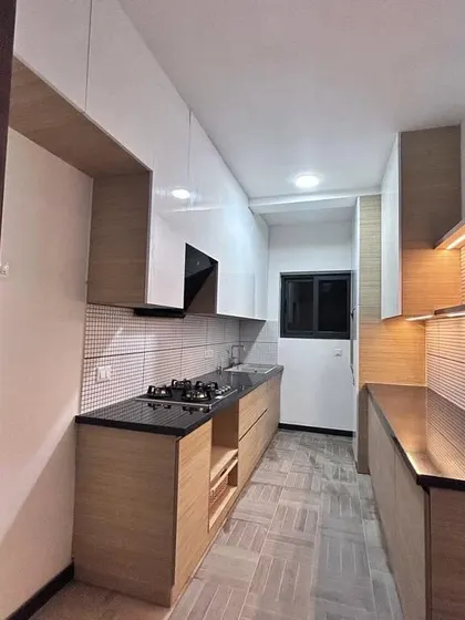 A parallel kitchen with a warm, natural aesthetic, featuring light wood grain cabinets and a tiled backsplash. This design is perfect for smaller spaces, providing ample storage without feeling crowded.
