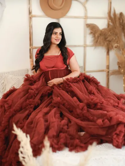 This stunning ruffled red gown makes for a truly glamorous maternity photo. The bright, bohemian inspired studio setup adds warmth and texture to the portrait.