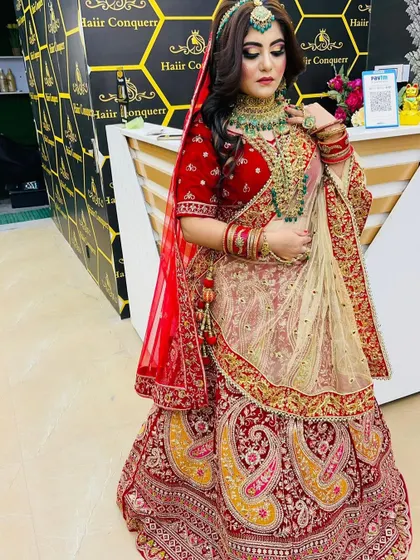 A full bridal jewellery set for rent. This bride is wearing a heavy red lehenga with a matching green-beaded kundan necklace, layered haar, and matha patti.