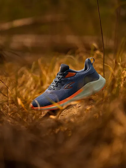 An outdoor shot of a running shoe in a field of dry grass. The shallow depth of field makes the shoe pop, while the natural setting emphasizes its use for outdoor activities.