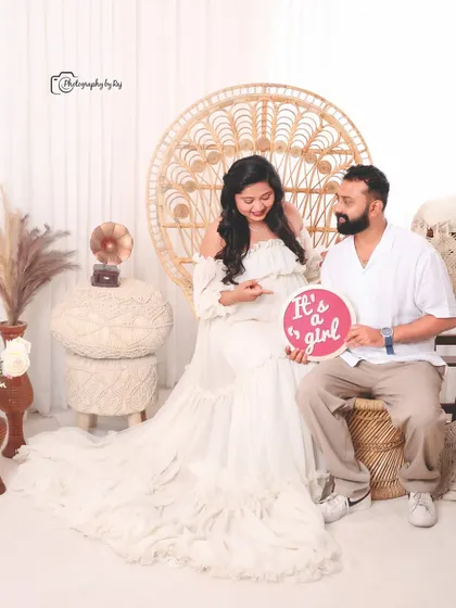 A happy gender reveal in our bohemian studio setup, with the couple holding a sign that says "It's a girl!".