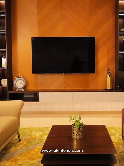 This living room features a stunning wood-paneled TV wall with a chevron pattern. The built-in shelves with backlighting are perfect for displaying books and decor, creating a warm and inviting focal point.