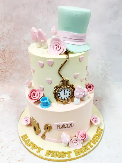 We invite you down the rabbit hole with this whimsical two-tiered Alice in Wonderland cake. Adorned with the Mad Hatter's hat, a pocket watch, and other iconic elements from the story, this pastel-colored creation is perfect for a magical first birthday tea party.
