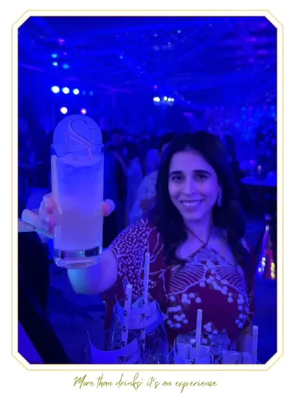 A guest enjoying her personalized cocktail under the cool blue lights of the party. The custom stirrer adds a special touch to her experience.