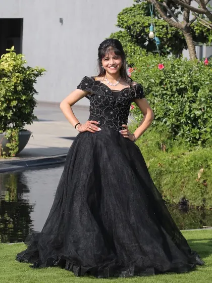 Elegance in black. This off-shoulder black ball gown with floral appliqué on the bodice is a sophisticated and timeless choice for any formal event.