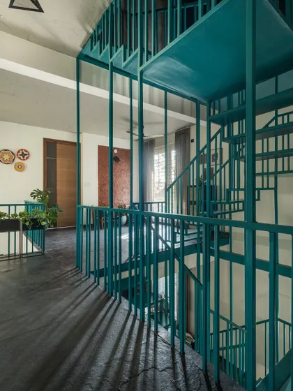 The play of light and shadow is a key design element. Here, the vertical lines of the blue staircase create striking patterns on the dark floor, which change throughout the day.