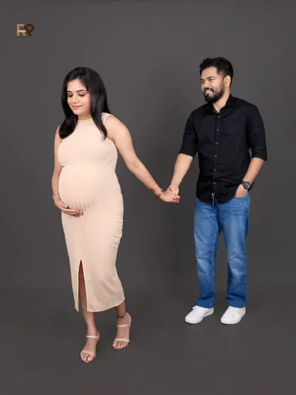 A walking pose that creates a sense of journey and movement. The couple holds hands, dressed in modern, casual attire, symbolizing their path into parenthood together.