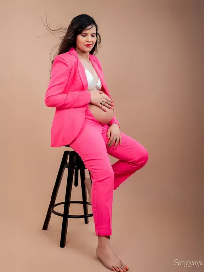 The wind in her hair adds a touch of dynamic energy to this modern, seated portrait. The pink suit is a bold and fashionable choice.