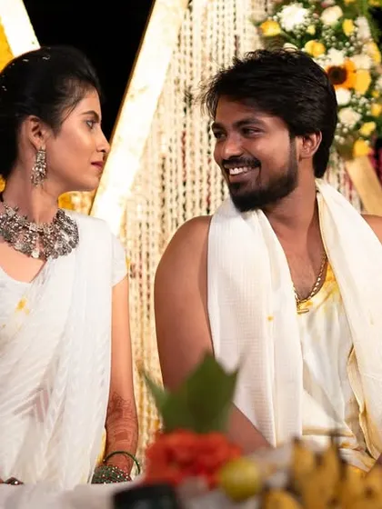 The couple shares a look of love and happiness, seated amidst the vibrant yellow decor of their Haldi function.