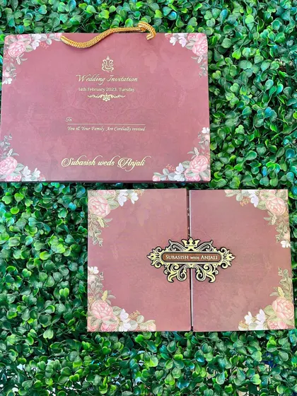 A beautiful dusty rose invitation with a floral border and a custom gate-fold design. The ornate metal nameplate adds a touch of luxury.